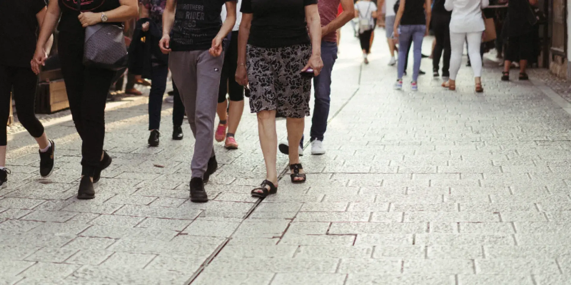 People walking down street, pictured from torso down