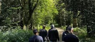 A group of people walking together on a path in a forest.